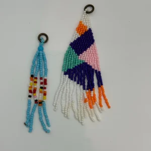 Two beaded earrings are hanging on a wall.