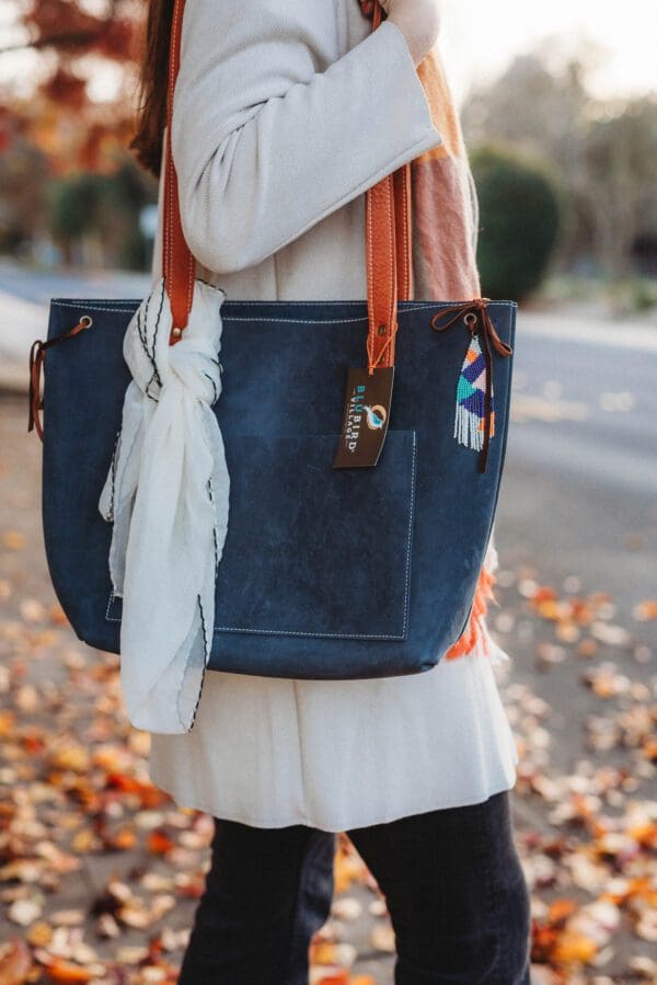 A woman is holding her purse and wearing a scarf.