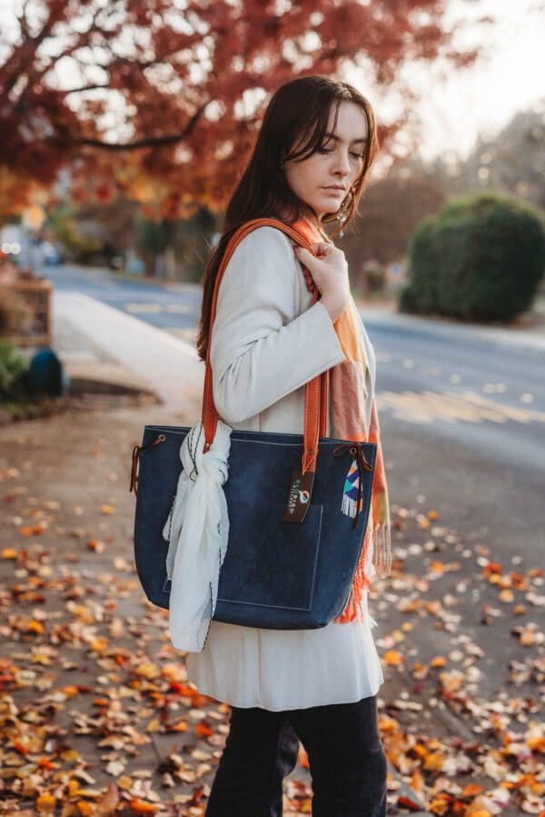 A woman standing on the side of a road with a purse.