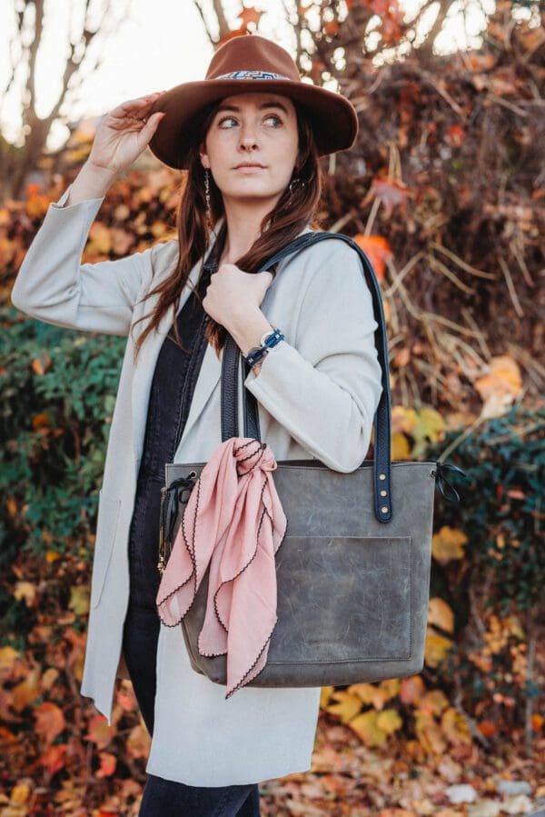 A woman holding onto her purse and wearing a hat