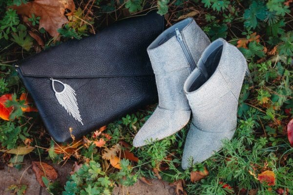 A pair of boots and purse sitting on the ground.