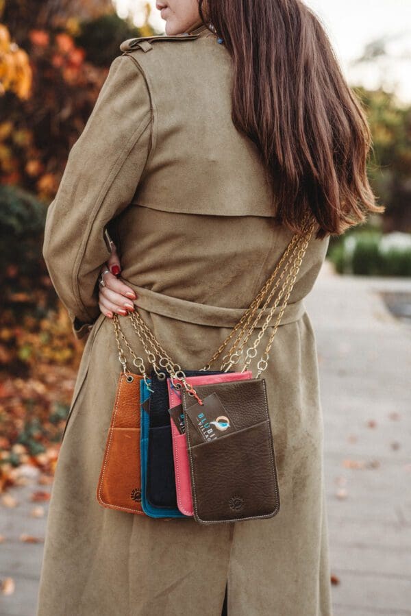 A woman in a trench coat holding onto some purses