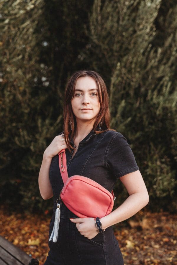 A woman standing in front of some trees holding onto her purse