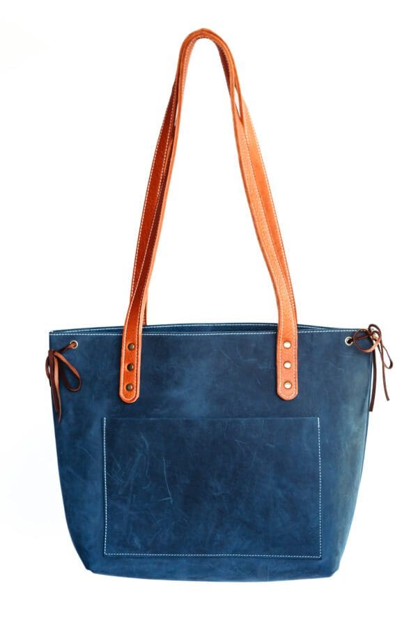 A blue purse with two handles and an orange strap.