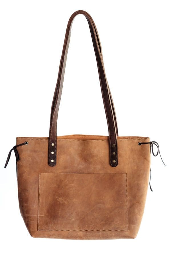 A brown leather bag with two handles and one side has a pocket.