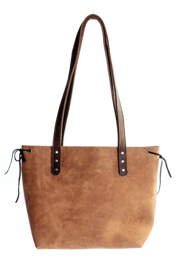 A brown leather bag with two handles and one on the other.