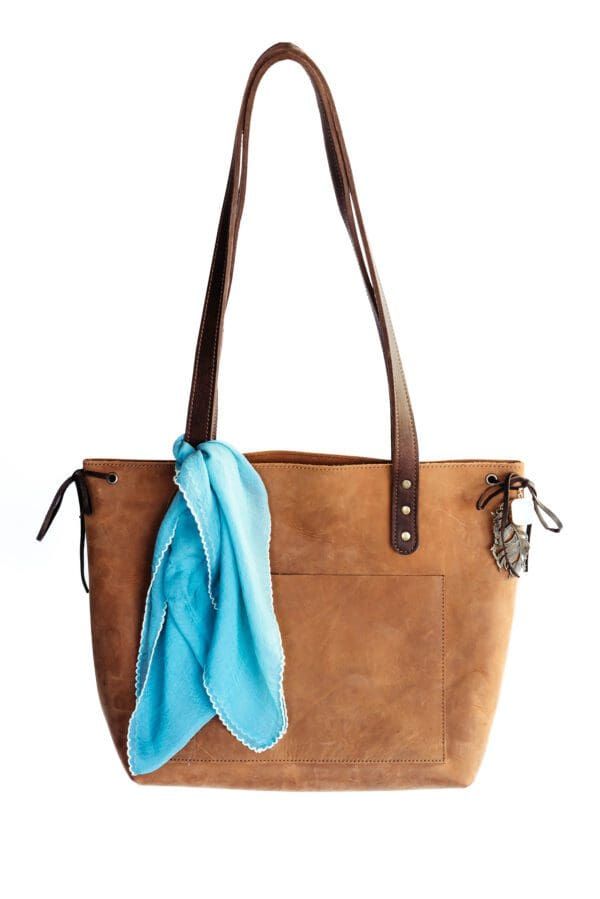 A brown purse with a blue scarf hanging on the side.