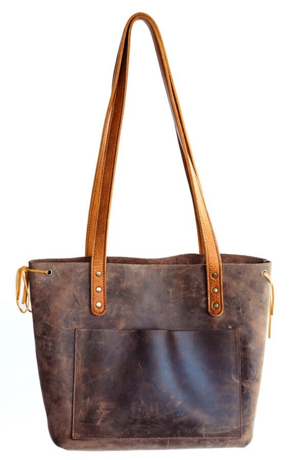 A brown leather bag with two handles and one side has a pocket.