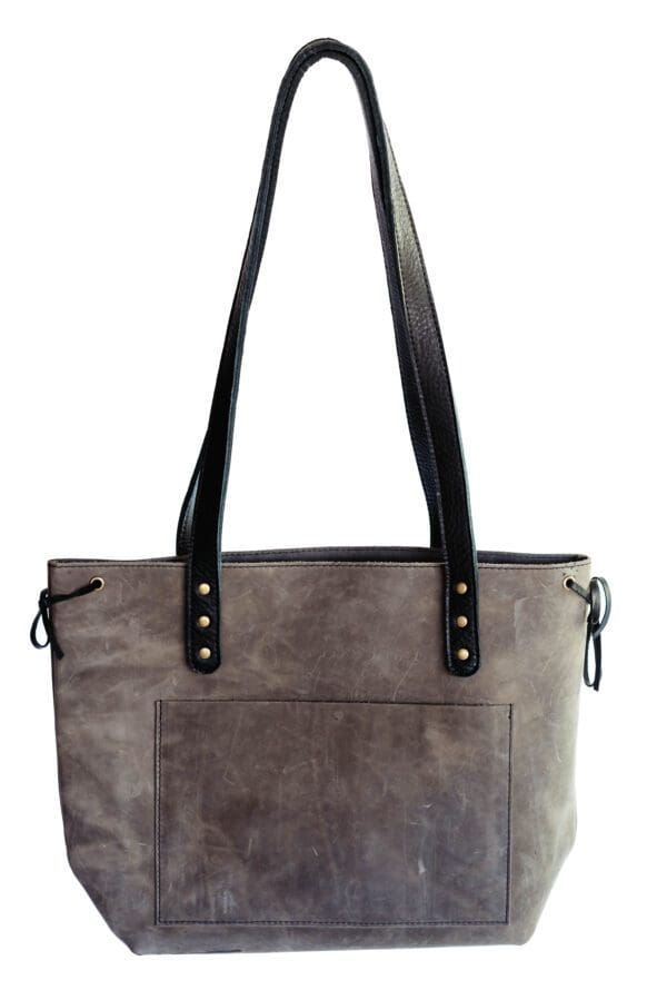 A gray purse with black leather straps and handles.