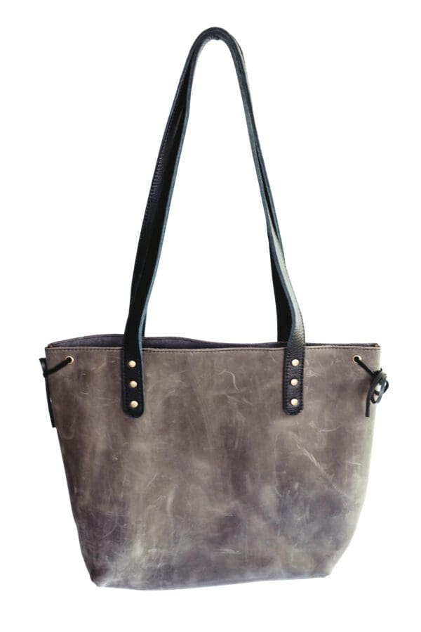 A gray purse with black handles and a strap.