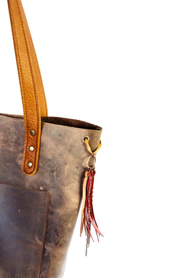 A close up of the handle on a brown leather bag