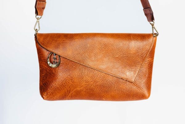 A brown purse with a strap hanging off of it.