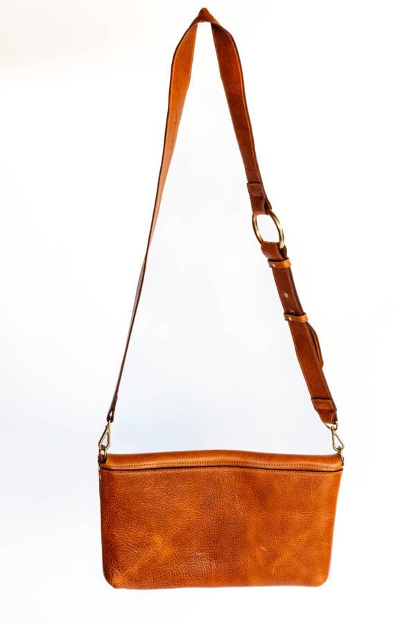 A brown purse is hanging on the wall.