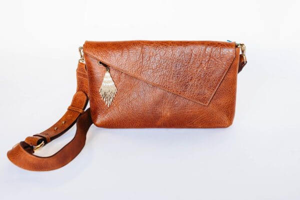 A brown purse with a leaf on the front.