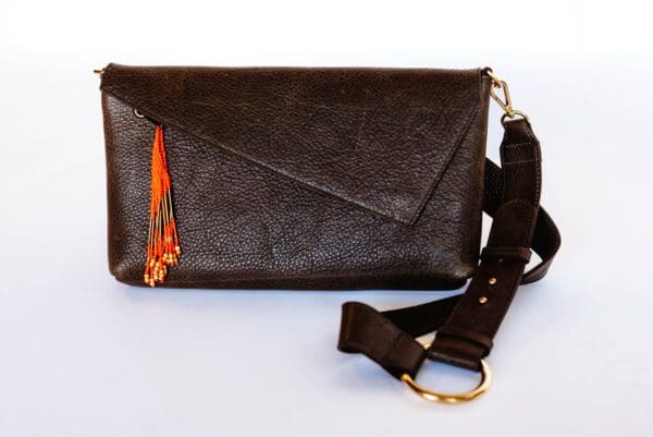 A brown leather purse with an orange tassel.