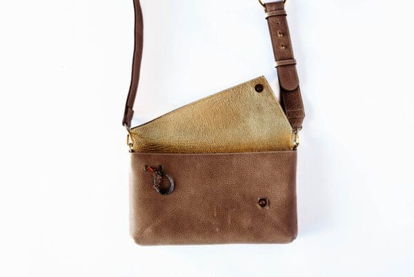 A brown purse is open and has a strap.