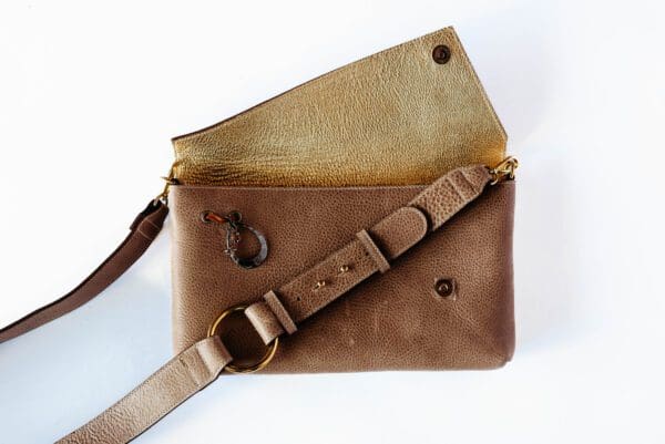 A brown leather purse with a strap on it.