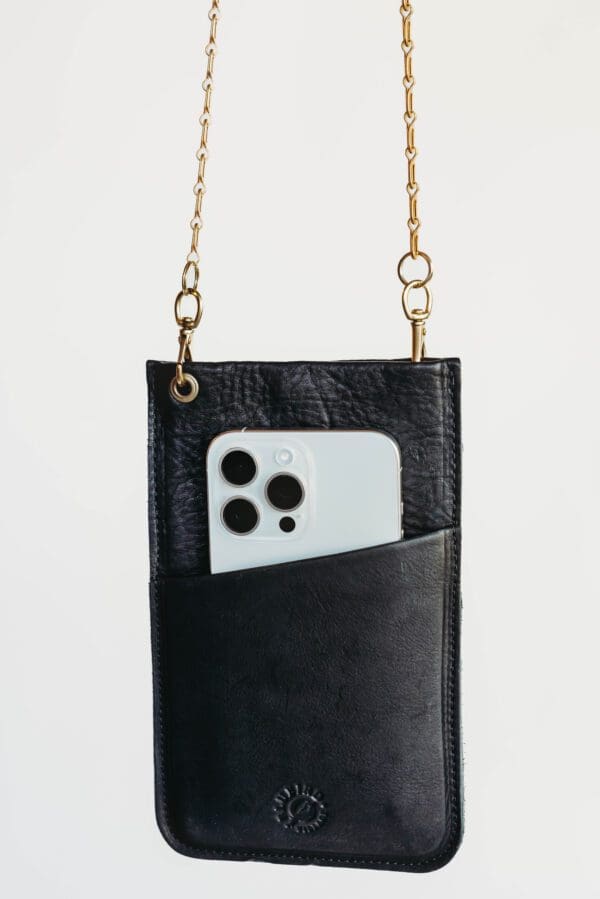 A black leather purse with a white phone in it.