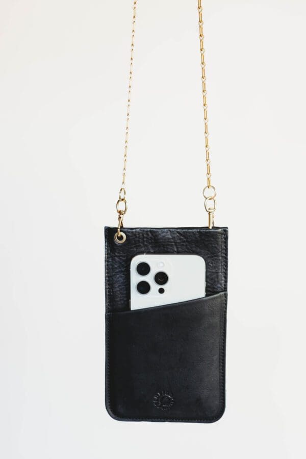 A black purse with a chain strap and a phone.