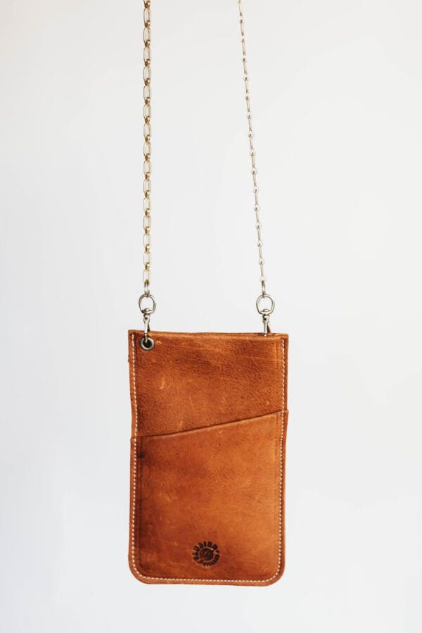 A brown leather purse hanging on a chain.