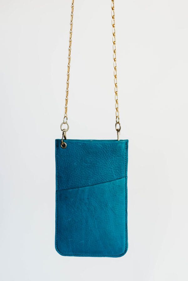 A blue purse with gold chain hanging from it.