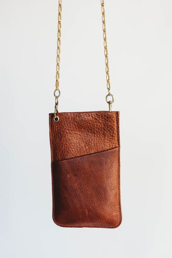 A brown leather purse hanging on a chain.