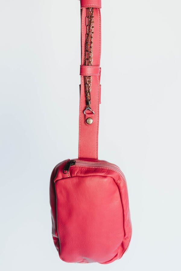 A pink bag with a strap hanging from it.