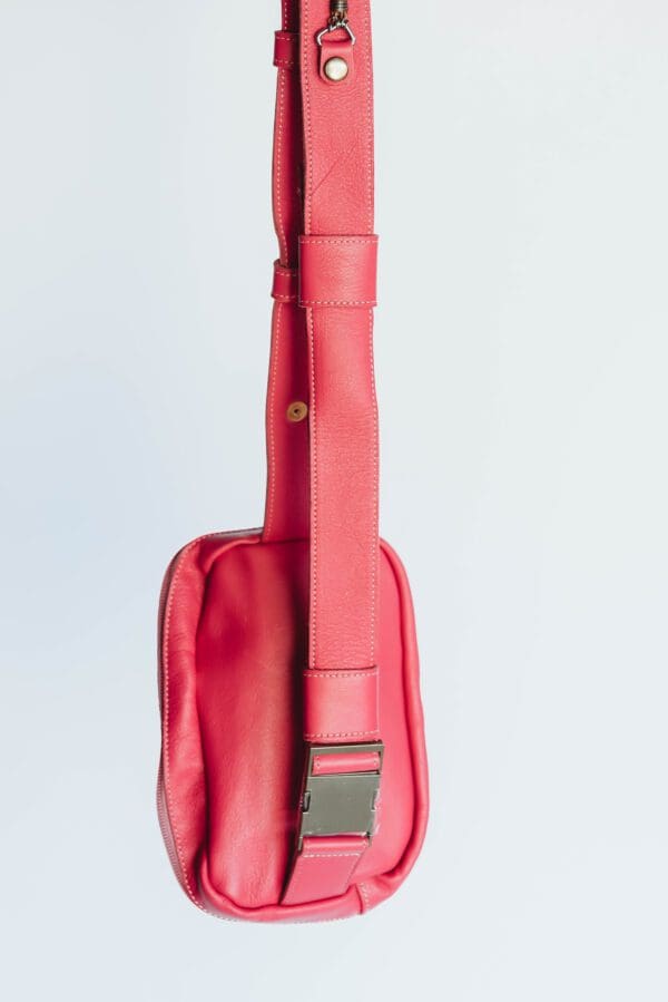 A red guitar case with a strap hanging from the side.