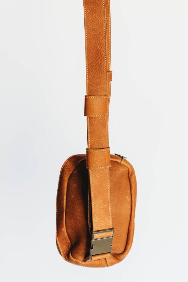 A brown guitar case with a strap hanging from the side.