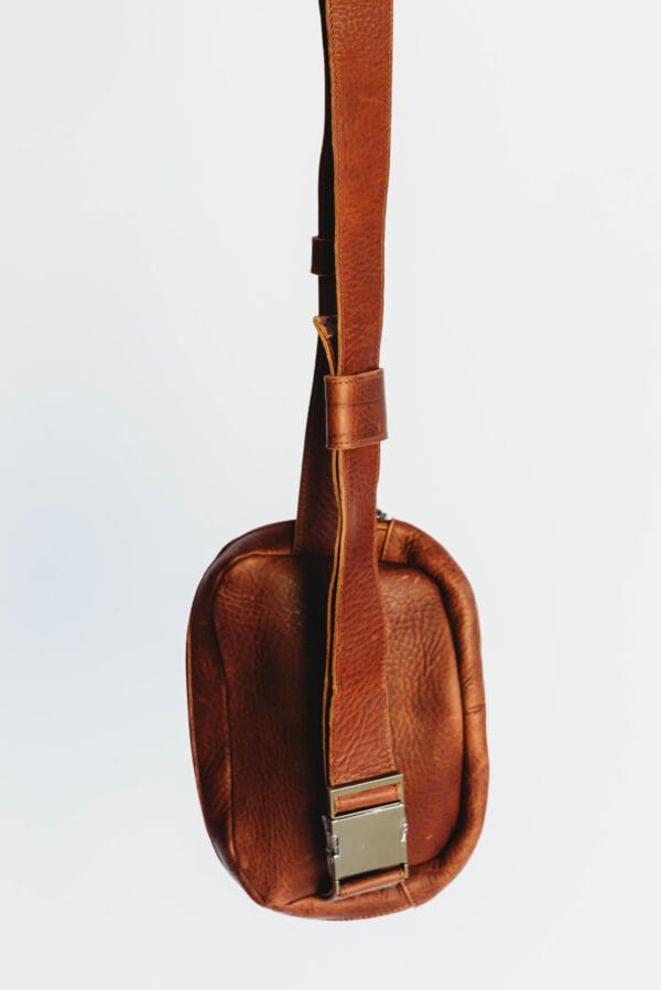 A brown leather bag with a strap on it.