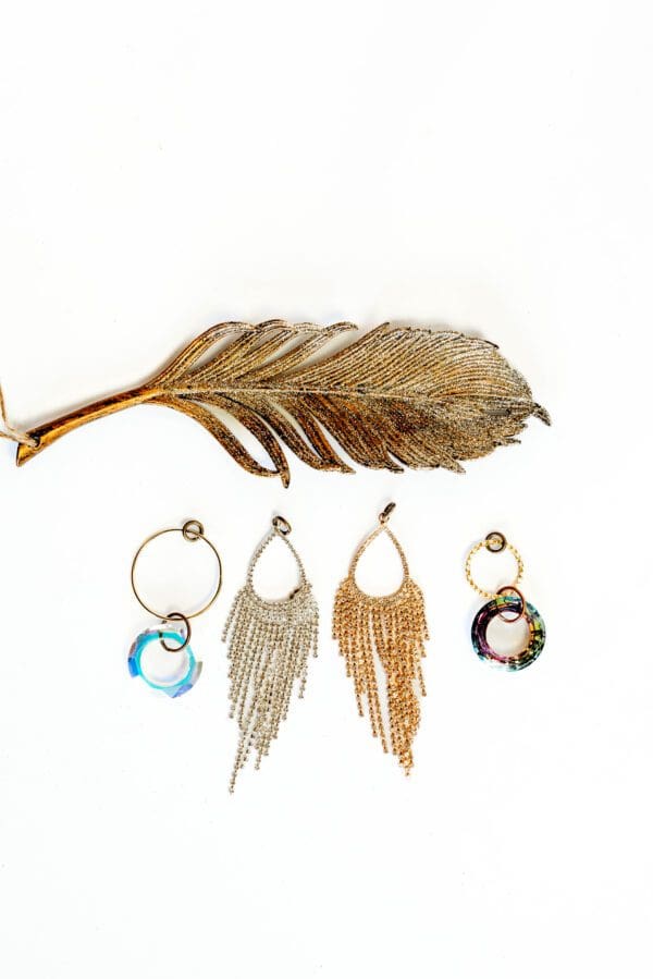 A feather and some earrings on a white background