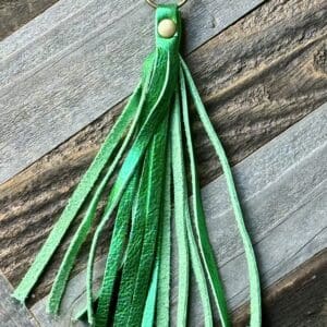 A green leather tassel on top of a wooden table.
