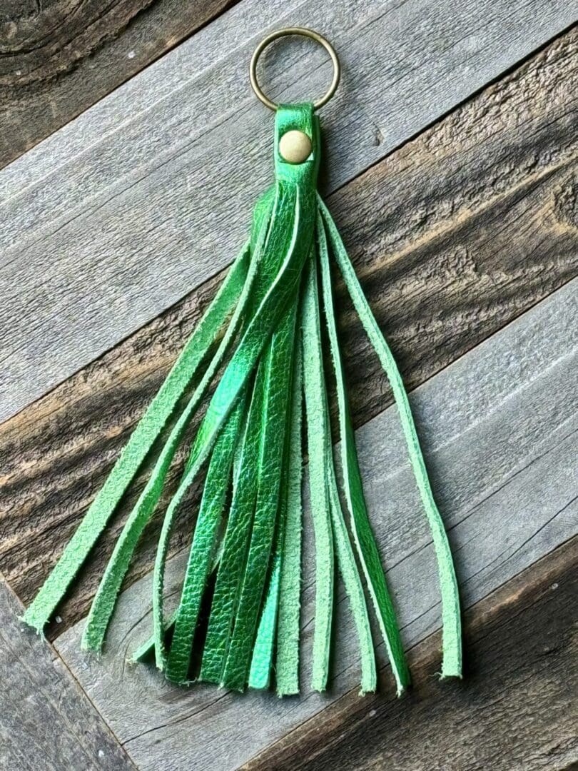 A green leather tassel on top of a wooden table.