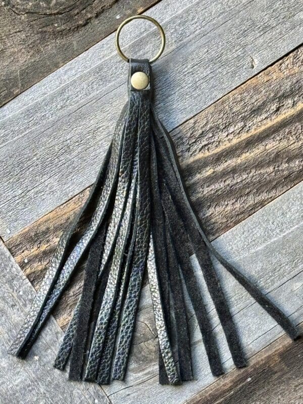 A black leather tassel keychain on top of a wooden table.