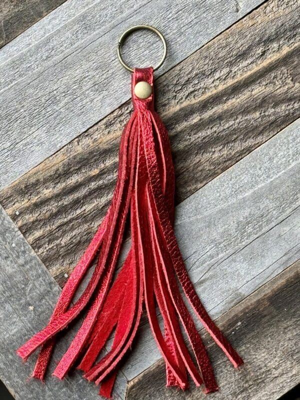 A red tassel keychain hanging on top of a wooden table.