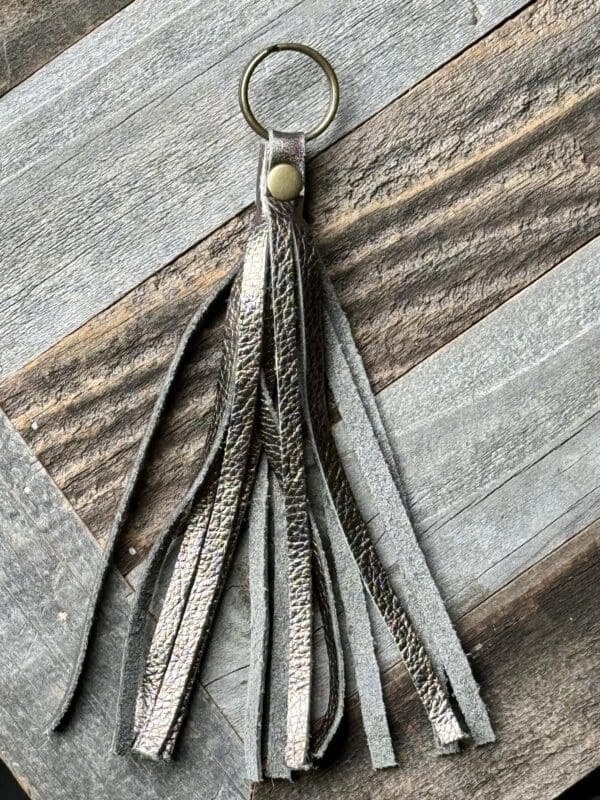 A leather key chain with tassels hanging on top of a wooden table.