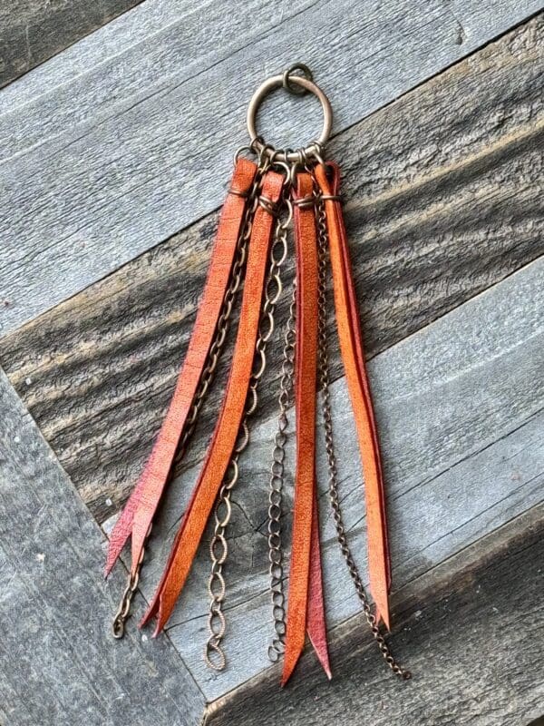 A leather keychain with chains and tassels.