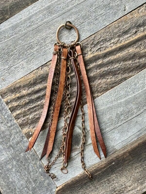 A brown leather key chain with chains hanging from it.