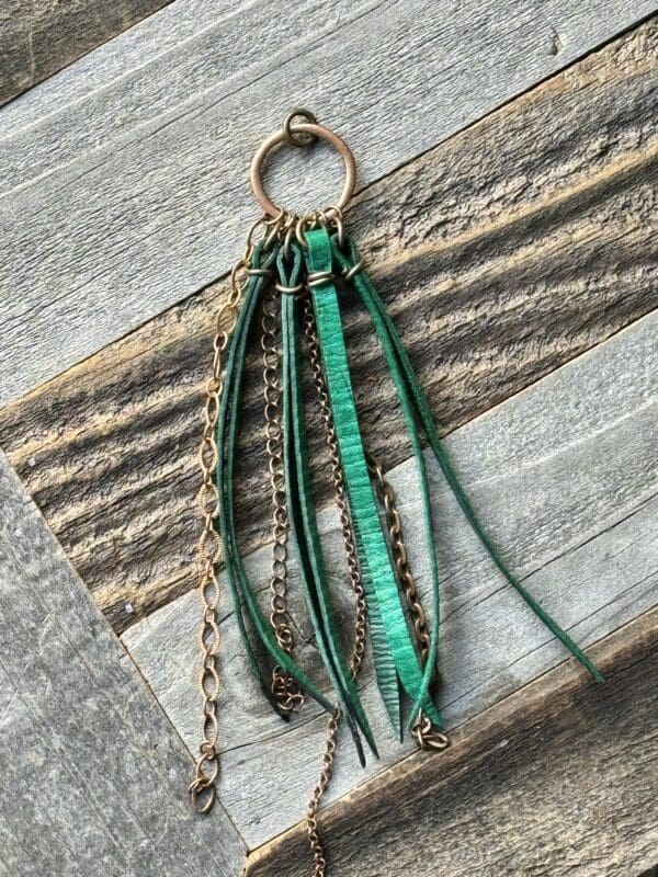 A green leather keychain with chains and tassels.