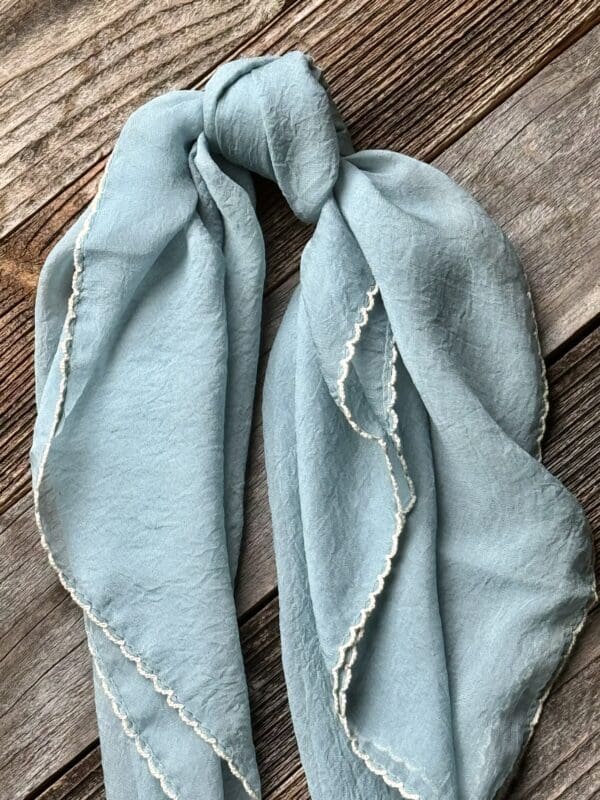 A light blue scarf with white stitching on it.