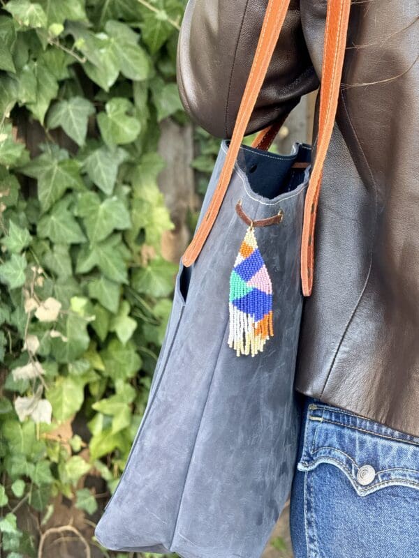 A person holding onto a bag with some colorful things hanging from it