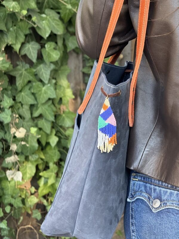 A person holding onto a bag with a colorful tie on it