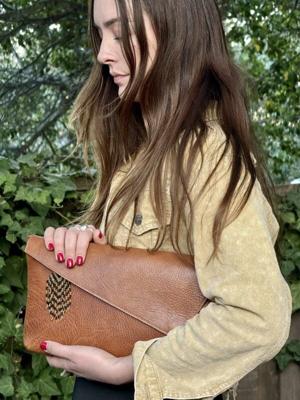 A woman holding onto a brown leather purse