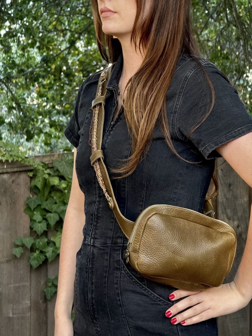 A woman wearing black and holding a brown purse.