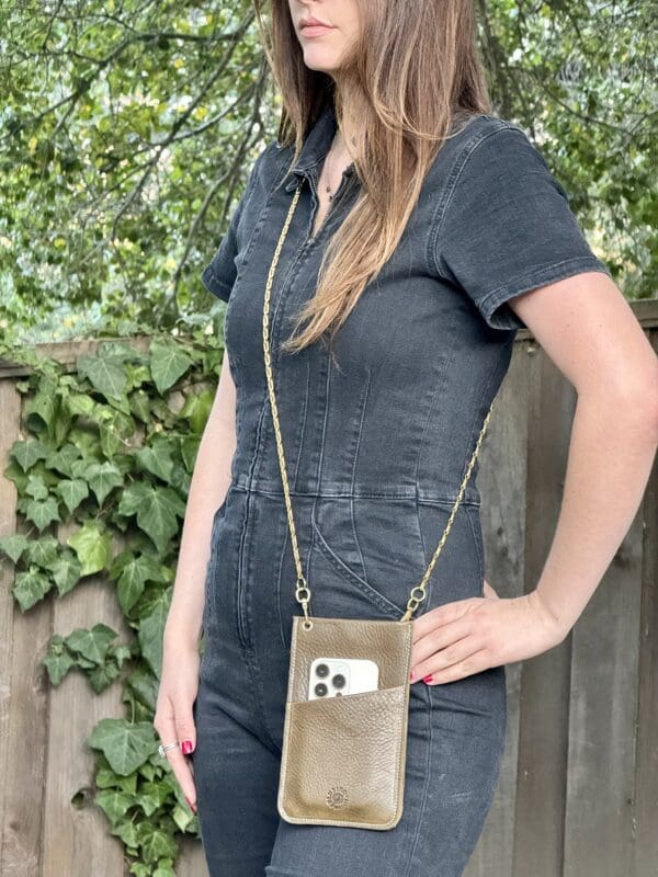 A woman standing in front of a fence holding onto a phone