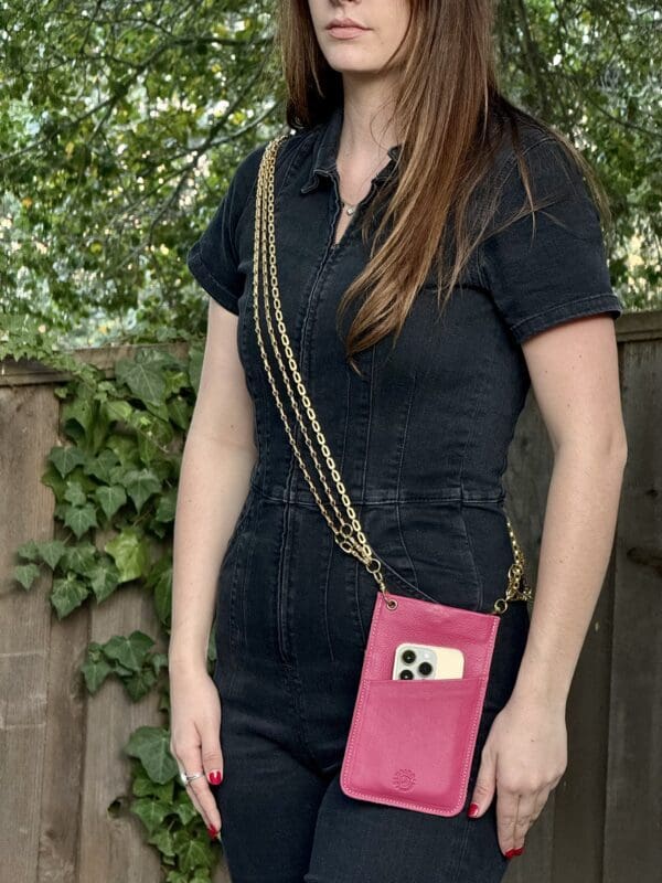 A woman standing in front of a fence holding her phone.