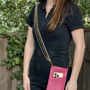 A woman standing in front of a fence holding her phone.