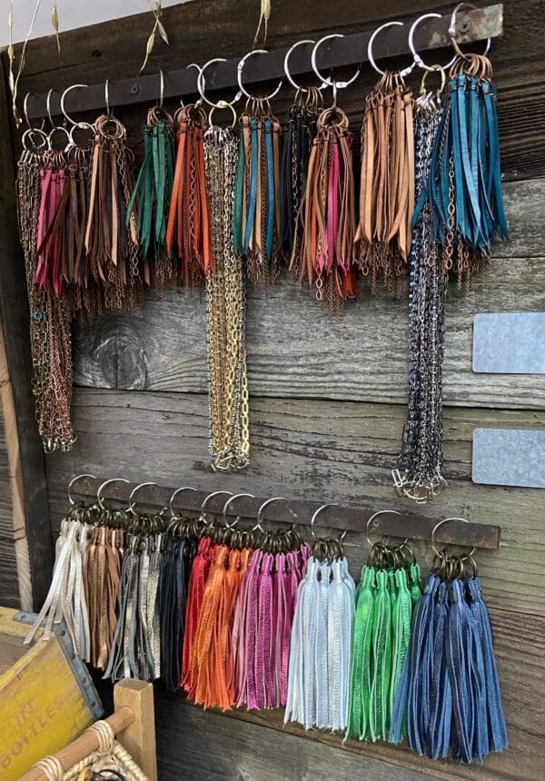 A wooden wall with many different colored tassels hanging on it.