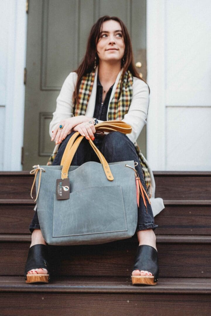 A woman sitting on steps with her purse.