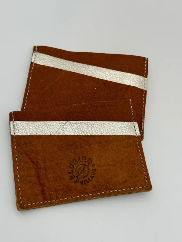 A pair of brown and silver wallets sitting on top of each other.